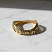 Bracciale Onda artigianale su marmo bianco — dettaglio texture rigata