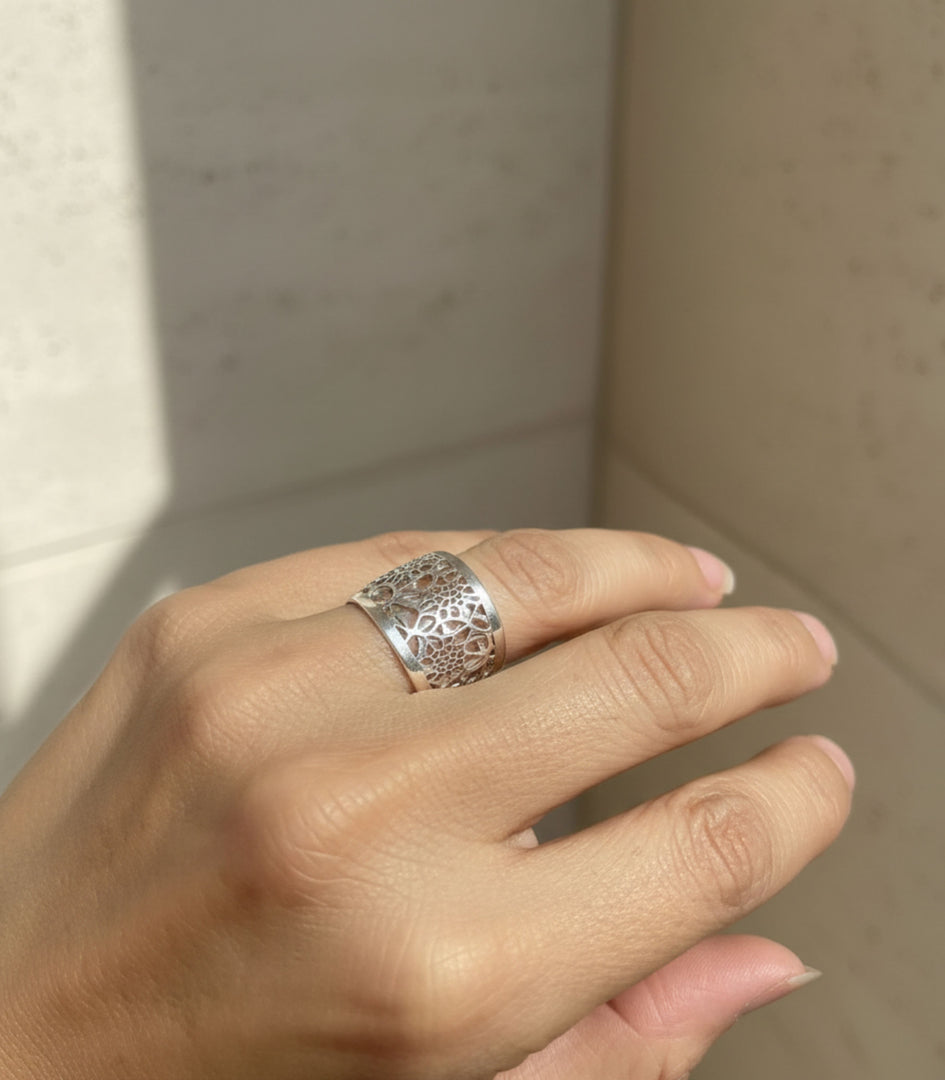 Anello Origine a fascia larga indossato su sfondo architettonico
